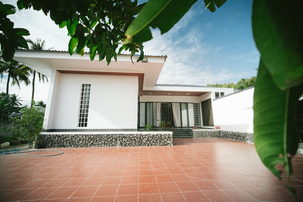 Architectural photo of a modern house with a tiled terrace under a clear blue sky.