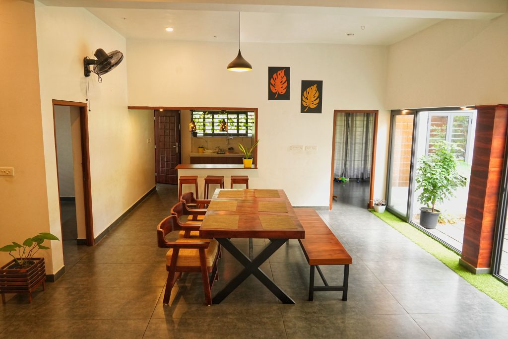 Modern dining area in a Kerala home featuring wooden furniture and vibrant decor.